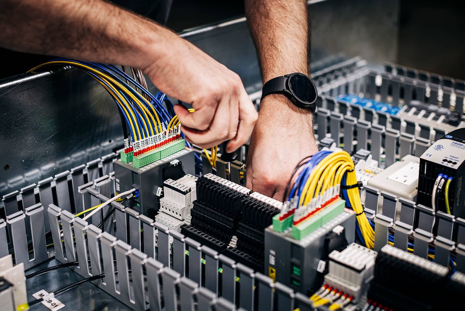 Endpoint technician wiring labeled terminal blocks inside a control panel